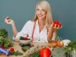 Healthy lifestyle concept with woman holding tomatoes and surrounded by fresh vegetables in a studio setting.